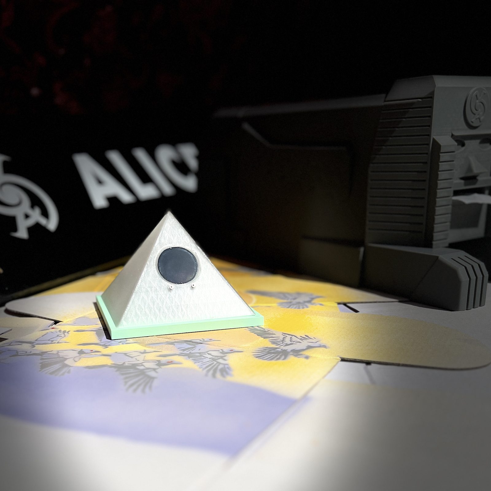The Oracle's pyramid — white and faintly glowing, its dark eye set in one face — standing in a pool of light, the sphinx's grey flank out of focus behind it